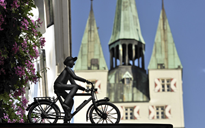 Fahrradfahrer an Hausfassade vor Stadtturm